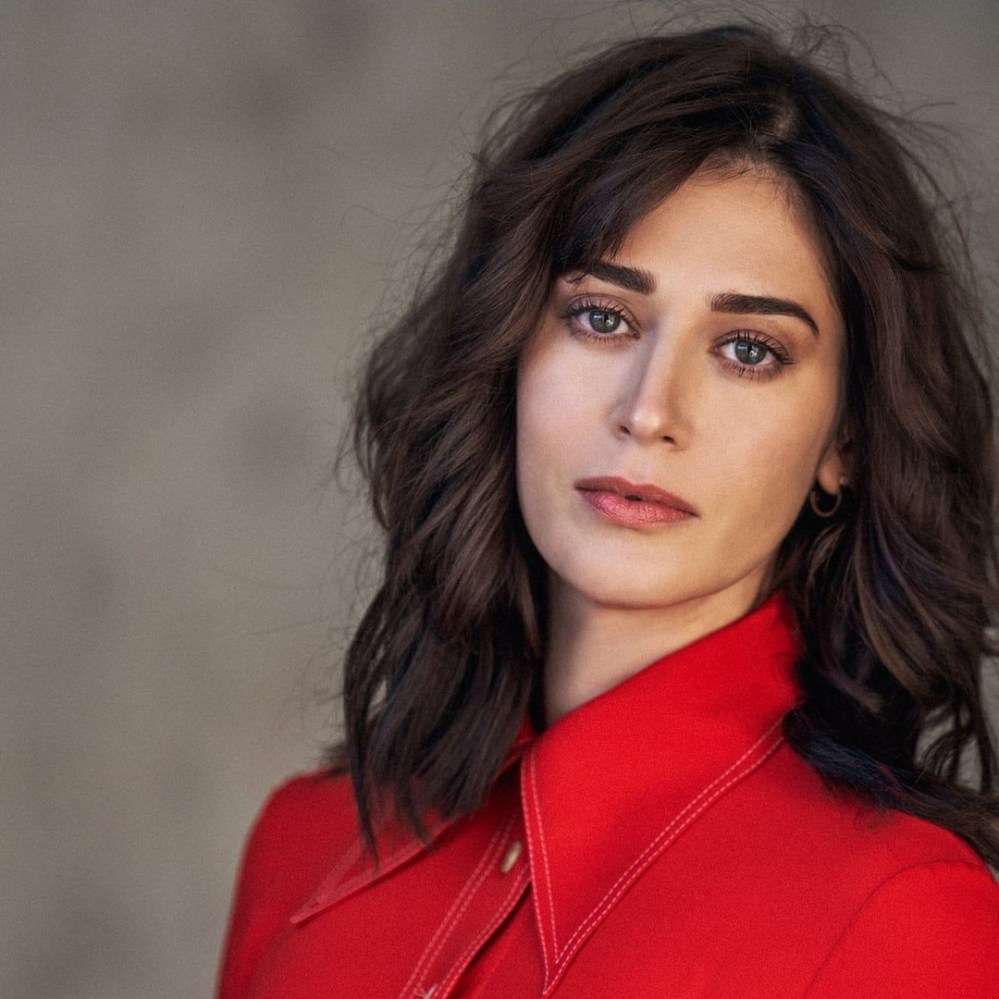 Portrait of a woman with wavy dark hair, wearing a bright red shirt, looking directly at the camera.