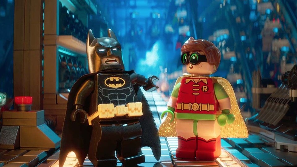 Two LEGO figures, Batman and Robin, are standing in a colorful, vibrant environment that resembles a superhero lair.