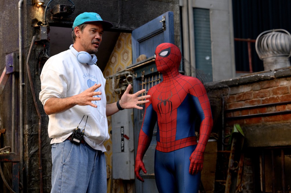 A director gestures while speaking to a person in a Spider-Man costume on a film set.