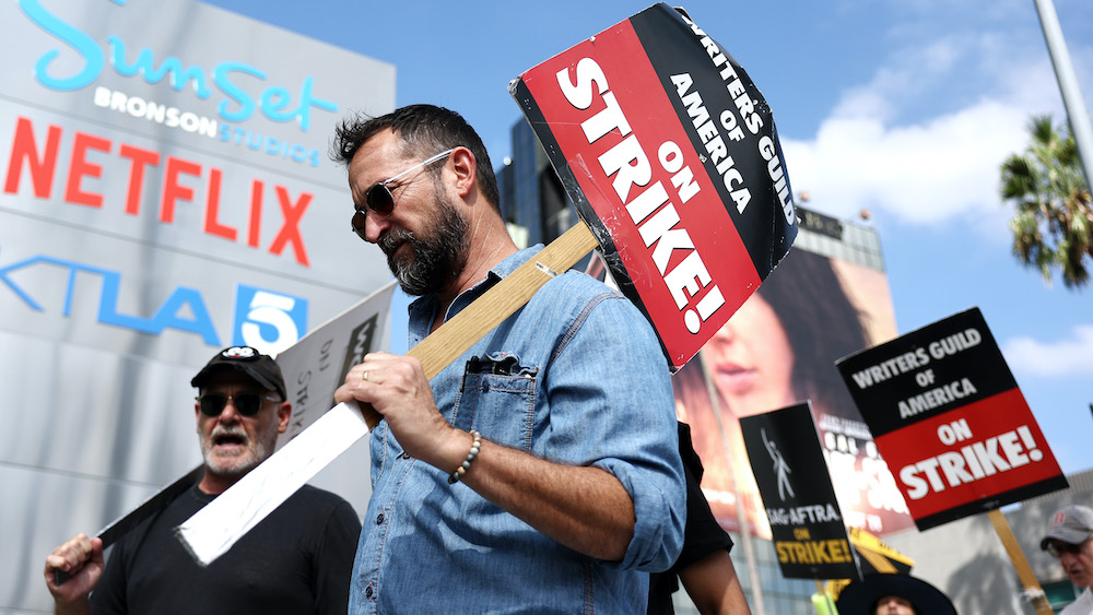 Demonstrators participating in a strike outside Sunset Bronson Studios, holding signs that read 'Writers Guild of America ON STRIKE!'