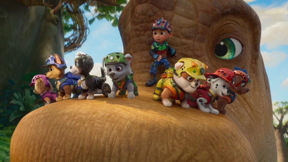 A group of animated puppies wearing colorful rescue gear, standing on the nose of a large dinosaur, with a child in a similar outfit nearby.